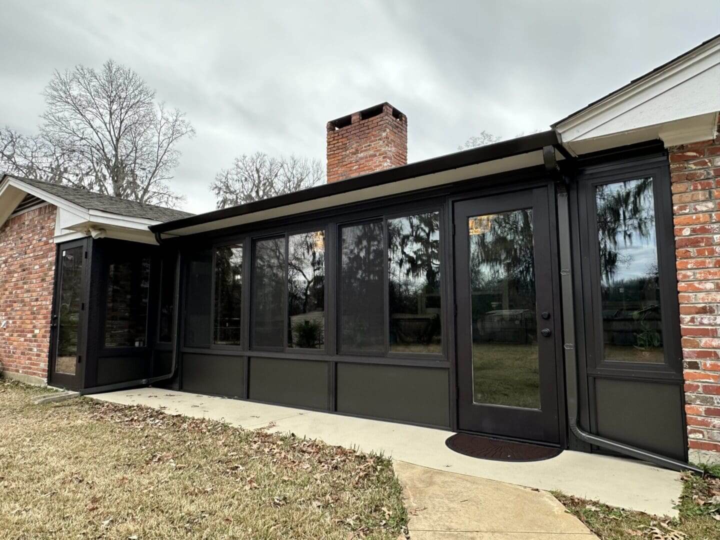 Brick house with dark-framed sunroom addition