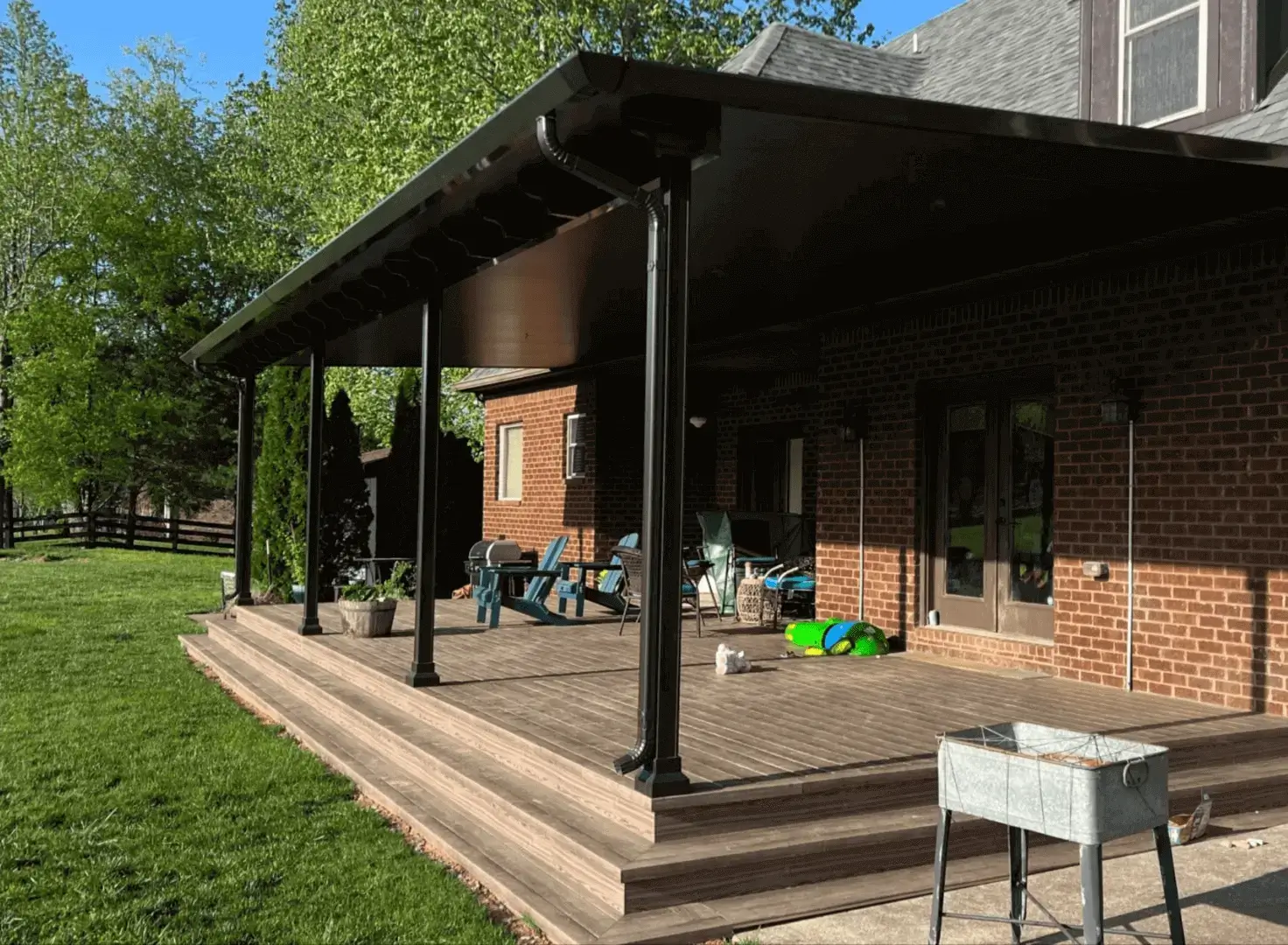 Covered backyard wooden deck with patio furniture